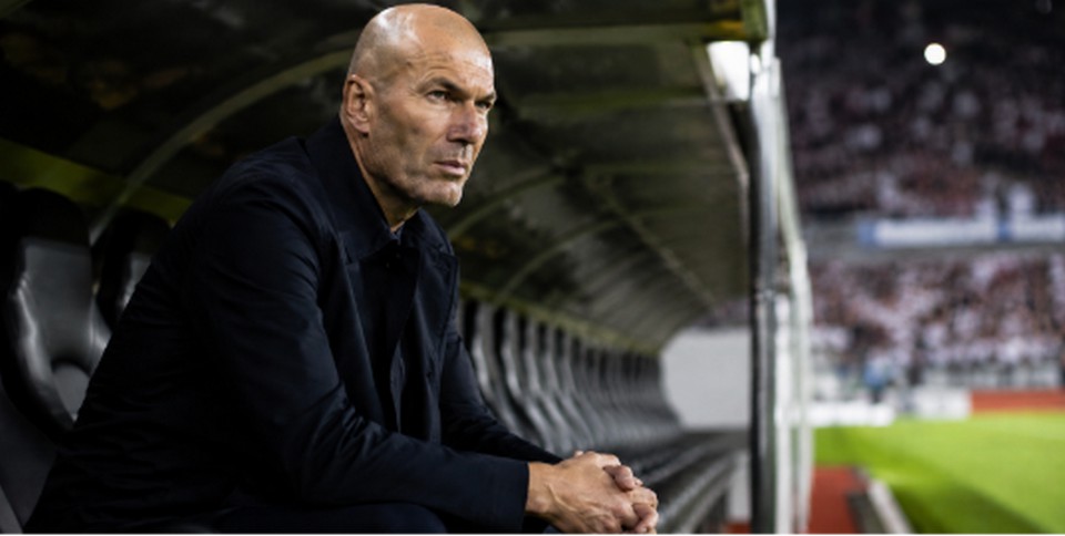 Zinedine Zidane sentado solo en el banquillo junto al campo de fútbol